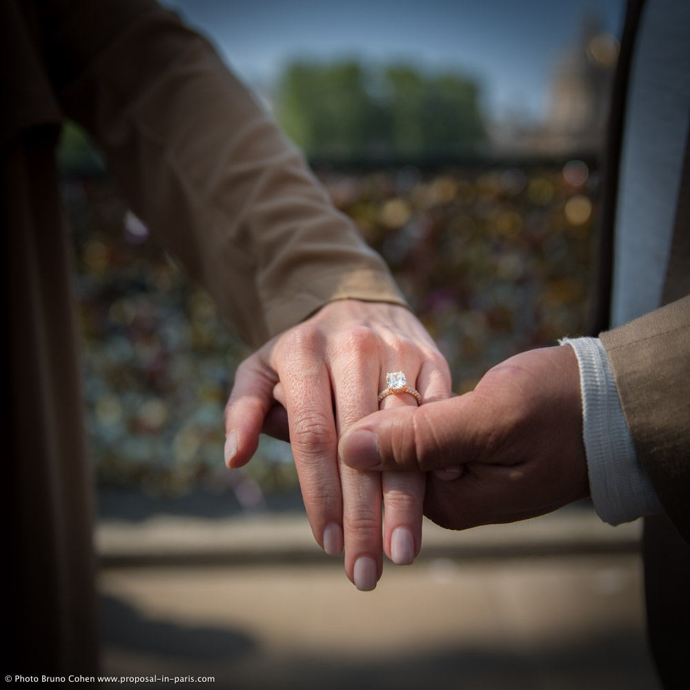 proposal in paris focus engagement ring couple hand in hand from locks bridge