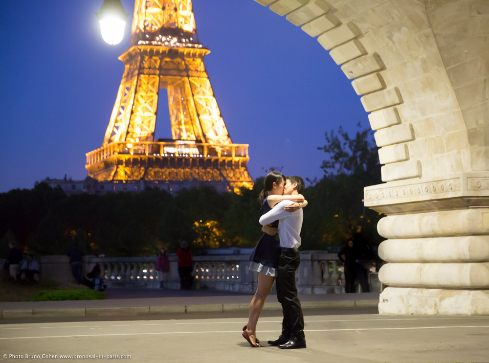 surprise proposal in paris by night front of Eiffel Tower from Bir Hakeim bridge couple in love