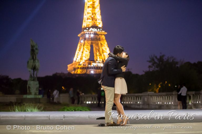 kissing couple from Bir Hakeim bridge front of Eiffel Tower sparkles by night proposal