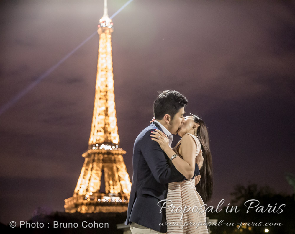 kissing couple in love from seine banks front of Eiffel Tower by night
