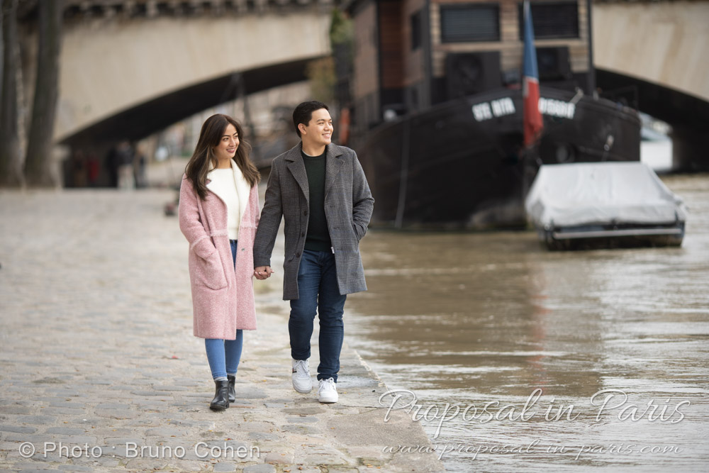 young couple walking along the river seine in Paris, Iena Bridge behind them