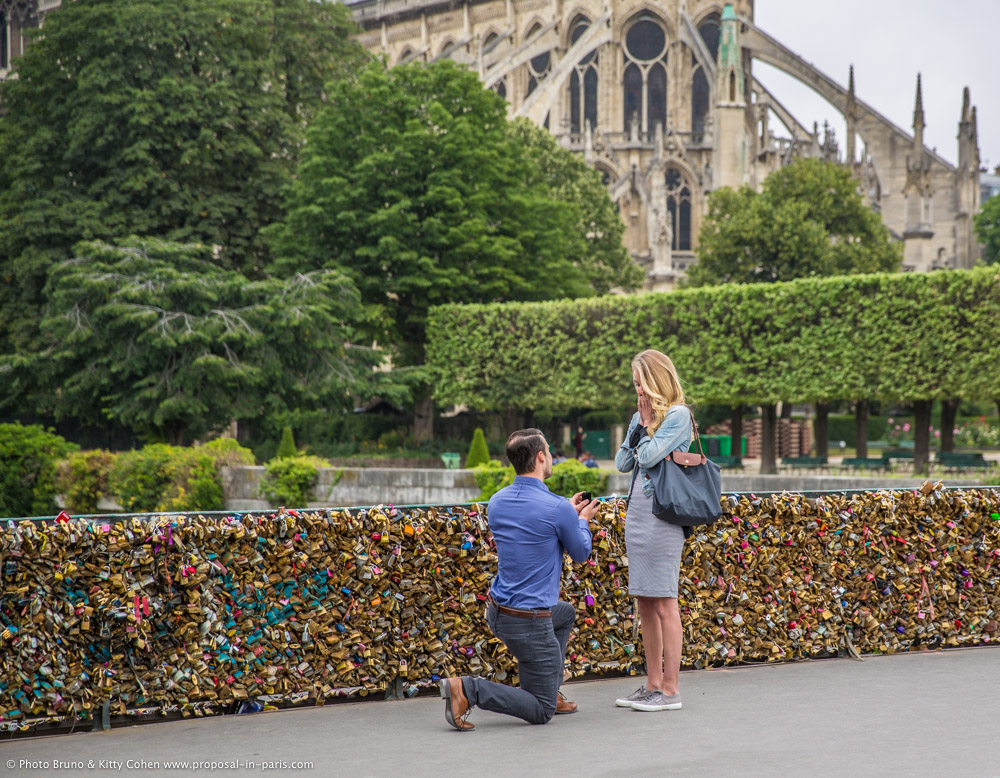 surprise proposal in paris from locks bridge front of notre dame cathedral