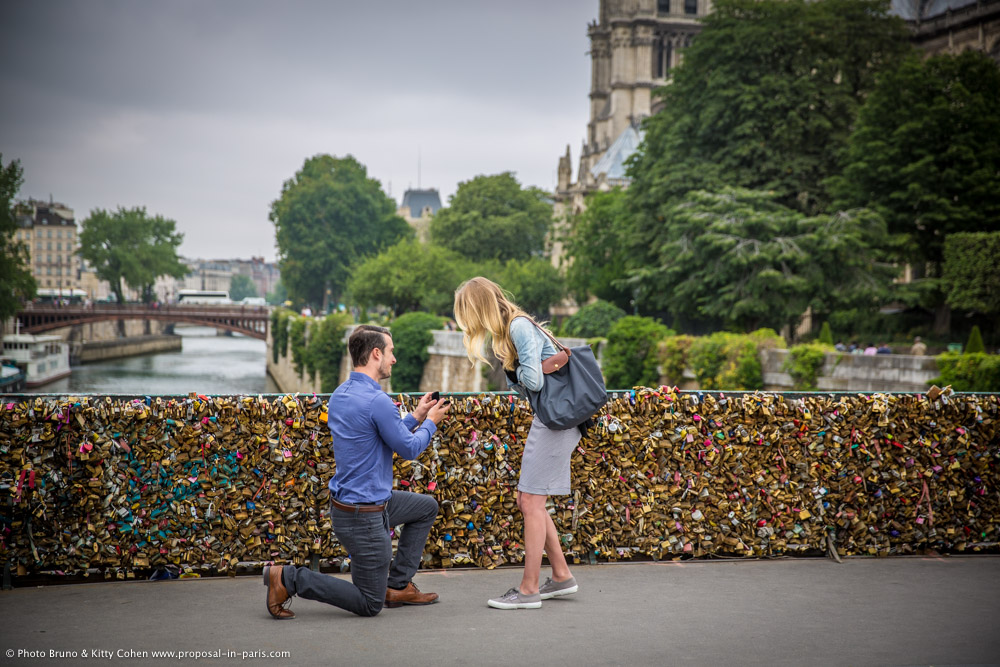 surprise proposal in paris from locks bridge front of notre dame cathedral lady cry