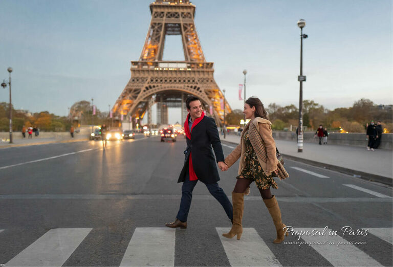 A couple crossing a road in front of the Eiffel Tower